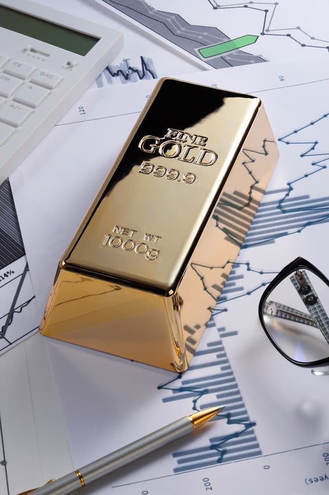 image de lingot d'or posé sur des feuilles contenant des graphiques