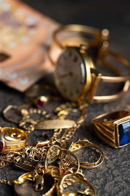 montre et bijoux en or sur une table avec un billet de 50 euros derrière